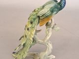 a figurine of a peacock sitting on a tree branch