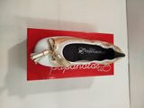 une chaussure dorée et blanche posée sur une boîte rouge