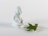 une figurine représentant un singe assis à côté d'une feuille