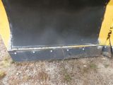a close up of a yellow and black snow plow sitting on top of a dirt field
