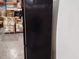 a black refrigerator in the middle of a warehouse