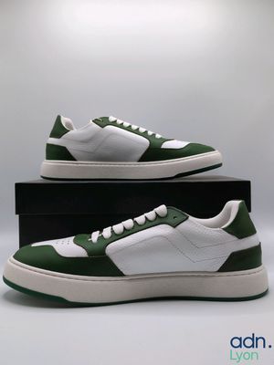 men ' s green and white sneakers with white soles on a black box