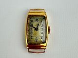a small gold watch with a white face on a white surface