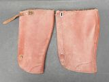 une paire de bottes d'équitation en cuir rose posées sur une surface grise