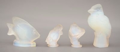 trois figurines d'oiseaux en verre et un oiseau posé sur une table