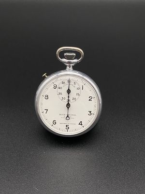 une montre de poche en argent posée sur une surface noire