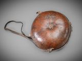 an old leather purse with a metal handle on a gray surface