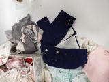 a pile of baby clothes on a shelf next to a toilet