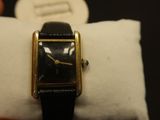 a black and gold watch sitting on top of a white pillow