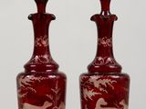 pair of red glass decanters with horses on them sitting on a table