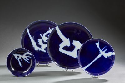 quatre assiettes bleues ornées de motifs blancs, posées sur une table