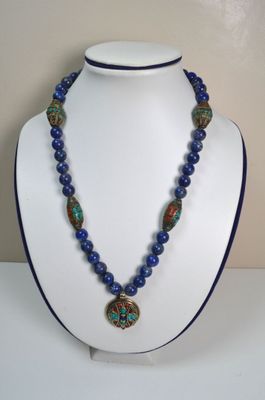 un gros plan d'un collier sur un mannequin, orné de perles bleues
