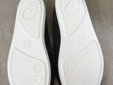 the bottom of a pair of black and white slippers on a couch