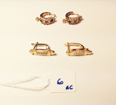 three pairs of earrings and a tag on a white surface