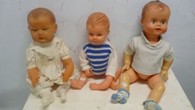 trois poupées assises sur une table blanche, vêtues d'un t-shirt rayé bleu et blanc