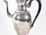 une théière ancienne en argent, dotée d'une anse noire, posée sur un socle