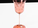 a pink wine glass sitting on top of a white table