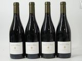 four bottles of red wine are lined up on a white surface