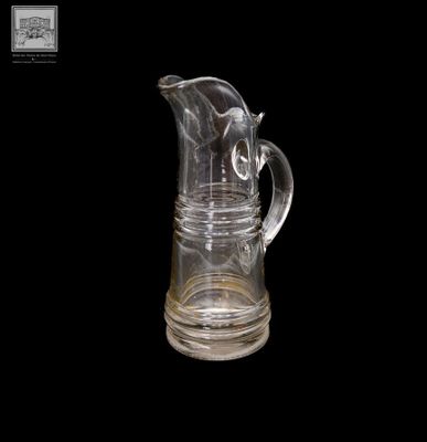 un pichet en verre transparent muni d'une anse, sur fond noir