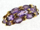 a close up of a ring with purple stones on a white surface
