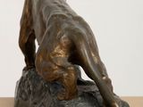 bronze statue of a dog on a rock on a table