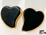 une paire de boucles d'oreilles noires et dorées en forme de cœur sur un fond blanc