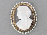 un gros plan sur une broche ornée de perles et représentant le visage d'une femme