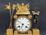 a gold clock with a statue of a man holding a flag