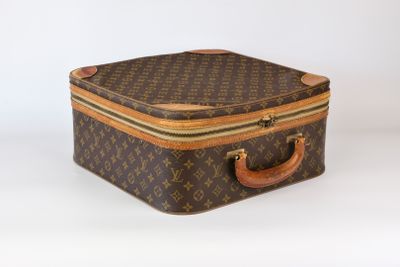 une valise marron et beige posée sur une surface blanche