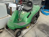 une tondeuse à gazon verte posée sur un chariot dans un jardin
