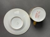 two white cups and saucers with gold rims on a table