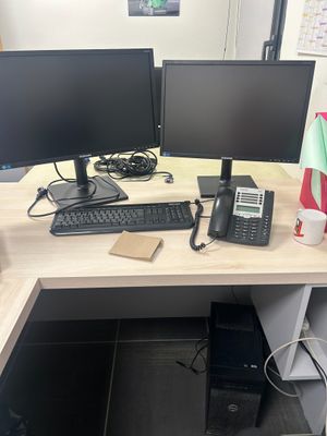 un bureau sur lequel se trouvent deux écrans d'ordinateur et un téléphone
