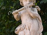 a statue of a boy playing a flute in the park