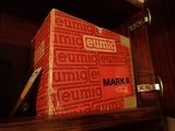 a red box sitting on top of a shelf next to a glass of wine
