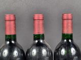 three bottles of red wine are lined up on a table