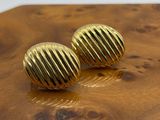 des boucles d'oreilles à tige plaquées or posées sur une table en bois, sur fond blanc