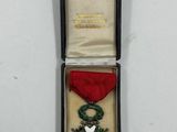 une petite médaille dans un écrin noir, accompagnée d'un ruban rouge