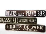 three street signs on a white background that read diners are piano bar, brasserie, and fruit de mer