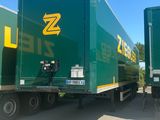 two green semi trailers parked in a parking lot