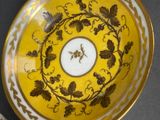 a yellow bowl with gold and white designs on it
