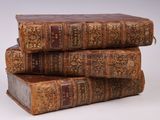 trois vieux livres empilés sur une surface blanche