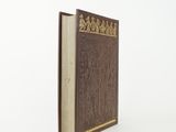 an old book with a brown cover sitting on top of a white surface