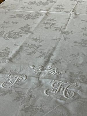 un lit recouvert d'un couvre-lit blanc orné de monogrammes