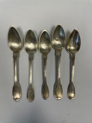 five silver spoons lined up in a row on a white surface