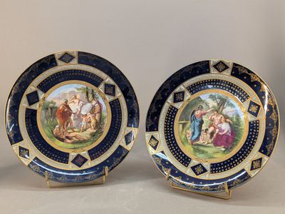 deux assiettes bleues et dorées ornées de motifs peints, posées sur une table