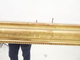 a man holding a large gold framed mirror in a room