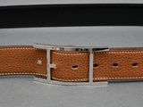brown leather belt with a silver buckle on a gray surface