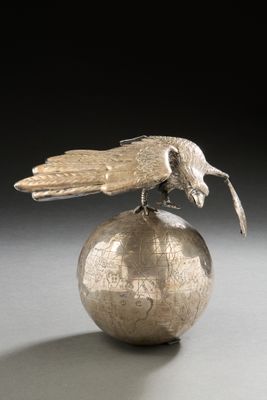 a silver bird sitting on top of a silver ball