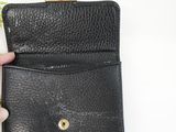 a hand holding a black purse with a gold clasp