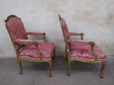 pair of pink upholstered chairs with gold trim and arms